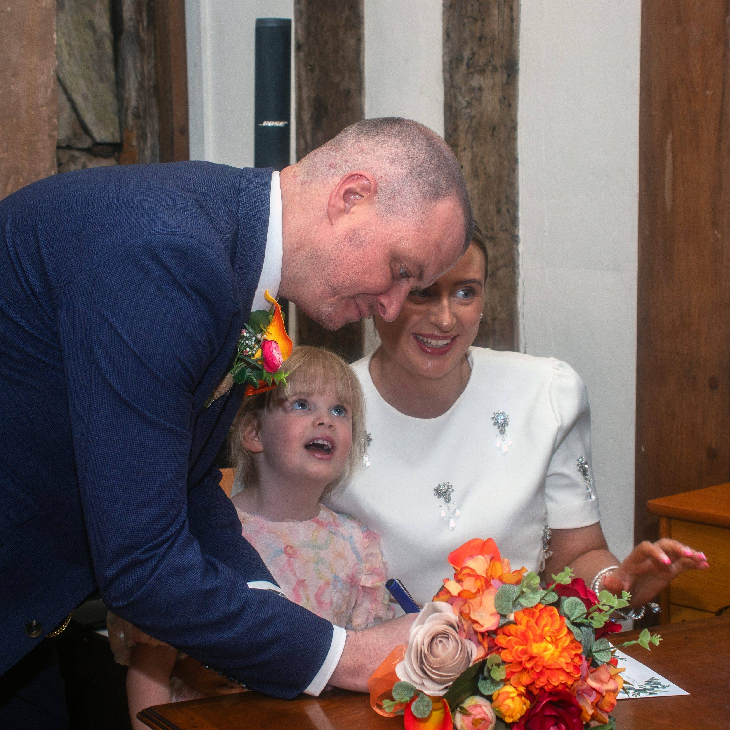 Signing the register with their daughter watching